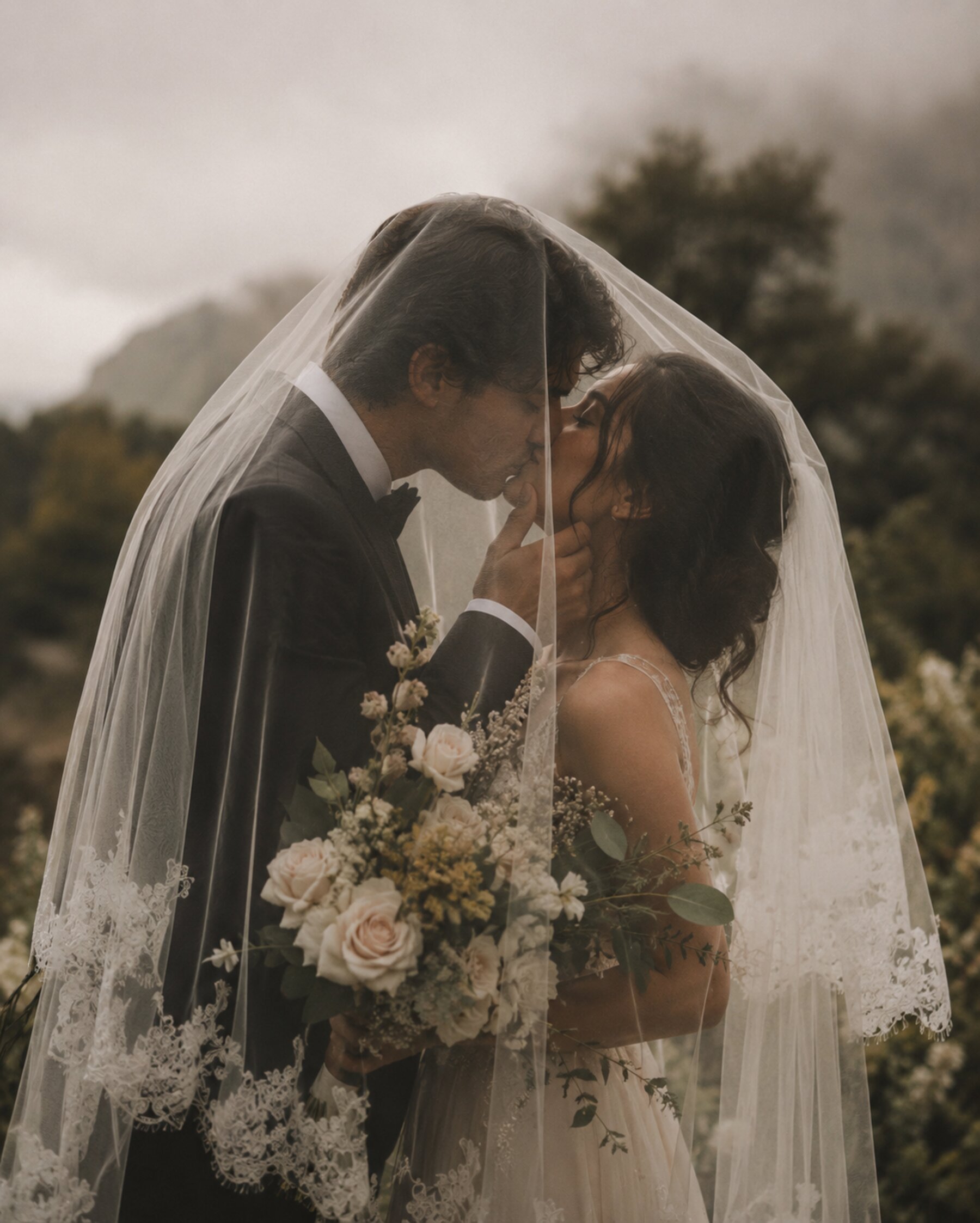 Bride and groom under a veil, holding a bouquet